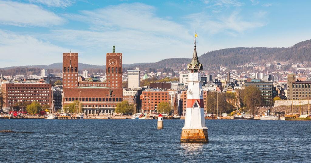 City hall and cityscape in Oslo, Norway, on a sunny day. Photo taken from the sea, with a blue sky on background. Travel and architecture concepts.