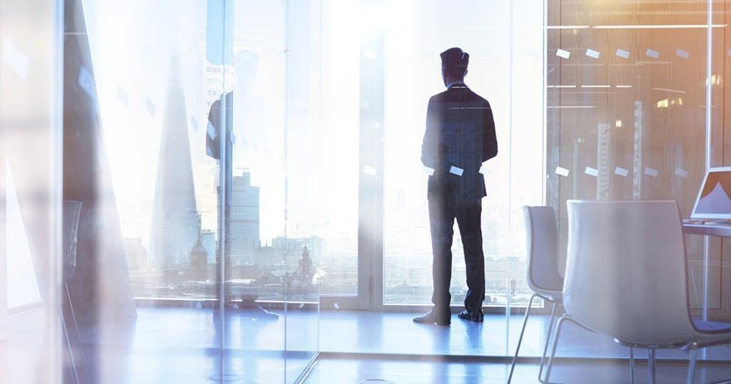 Businessman looking out of office over city