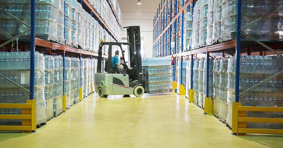 Worker moving pallets with forklift in warehouse