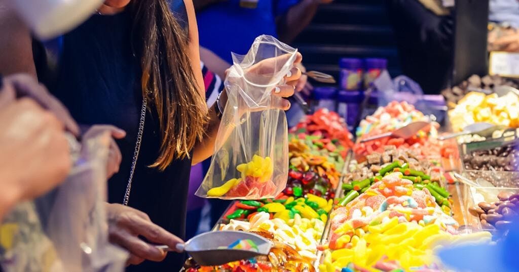Customers choose sweets from counter with assorted colorful different shape jelly candies on market place in Tel Aviv, Israel. Selective focus, space for text